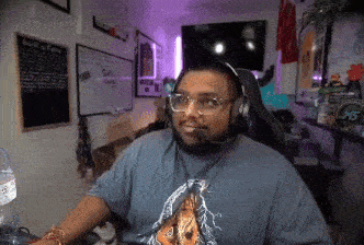 a man wearing headphones and a t-shirt with a lightning bolt on it is sitting in a chair