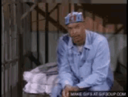a man in a blue shirt and hat is sitting on a bench .