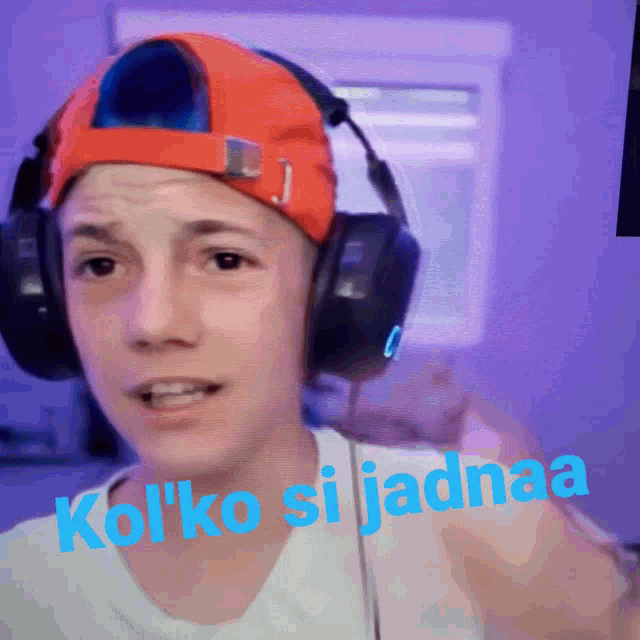 a man wearing headphones and an orange hat says " kolko siijadhaa " on the bottom