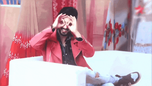 a man in a red jacket is sitting on a couch