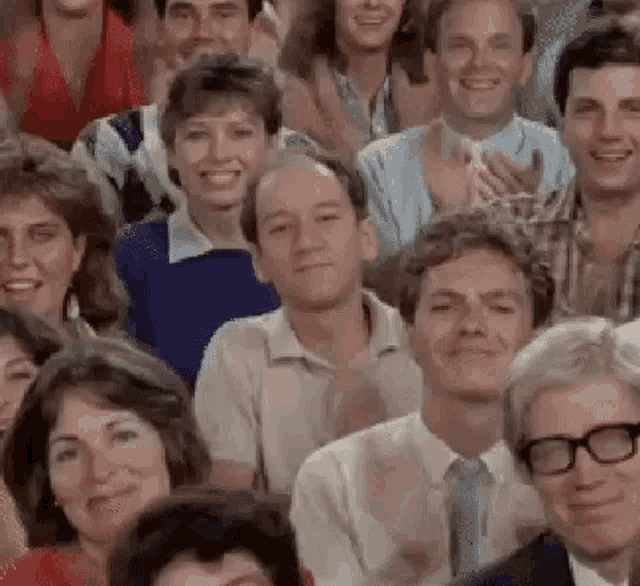 a group of people are sitting in a room clapping their hands .