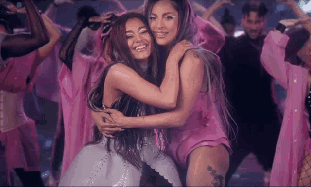 ariana grande and lady gaga are hugging each other in front of a crowd