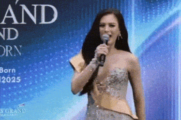 a woman in a dress is holding a microphone in front of a blue background .