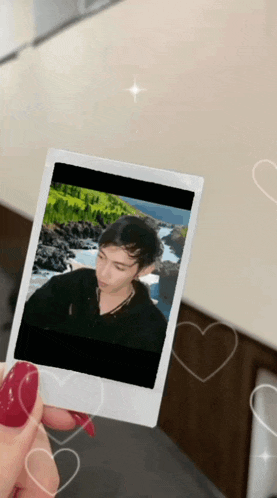 a person holding a polaroid picture of a man