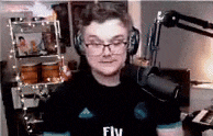 a man wearing headphones and a fly shirt is standing in front of a microphone .