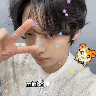 a young man is making a peace sign with his fingers while a hamster is on his face .