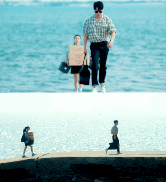 a man carrying a cardboard box walks by a woman carrying a black bag