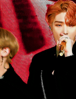 a man with red hair is singing into a microphone with a woman behind him
