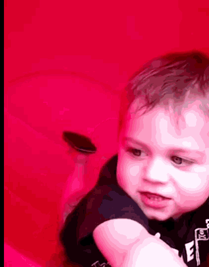 a young boy is laying on his stomach in front of a red background .