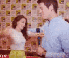 a man in a blue shirt is talking to a woman in a white top and yellow skirt .