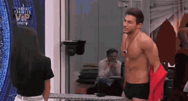 a man without a shirt is standing in front of a woman in a room .