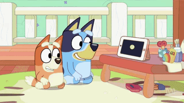 two cartoon dogs are sitting next to each other and looking at a tablet