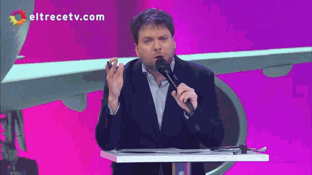 a man speaking into a microphone with eltrecetv.com written on the bottom
