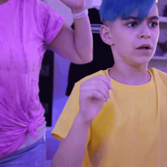 a boy with blue hair is standing next to a woman in a purple shirt