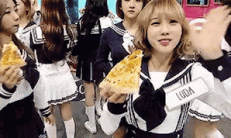 a girl in a sailor suit is holding a slice of pizza in her hand .