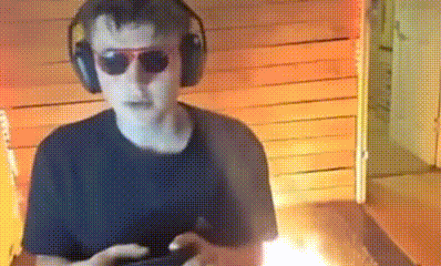 a man wearing headphones and sunglasses is playing a video game on a cell phone .