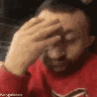 a man with a beard is holding his hand to his forehead .
