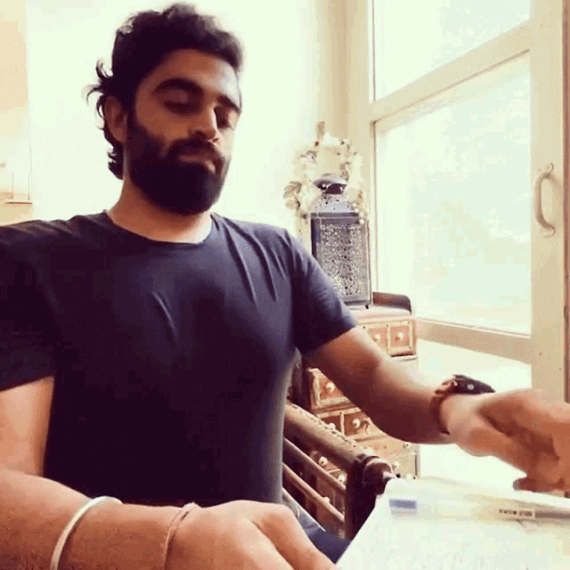 a man with a beard wears a black shirt and a watch
