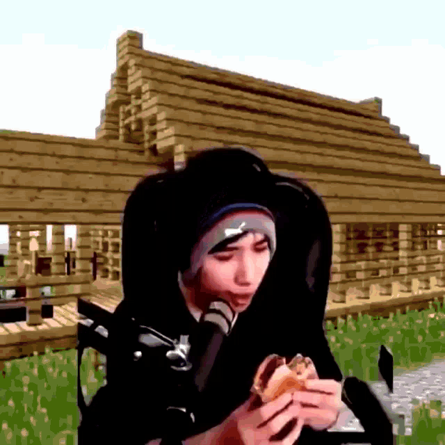 a man is eating a hamburger in front of a microphone in a minecraft world .