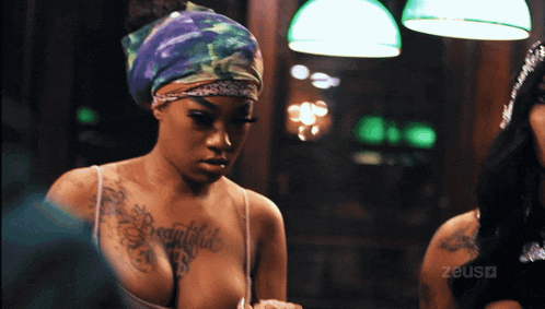a woman with a tattoo on her chest that says beautiful is looking at herself in a mirror