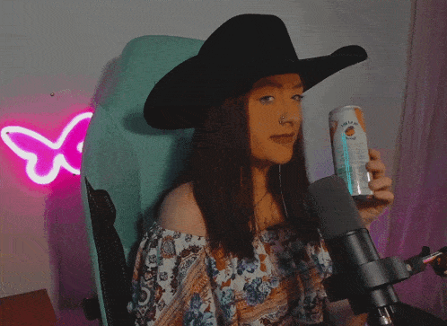 a woman wearing a cowboy hat drinks from a can