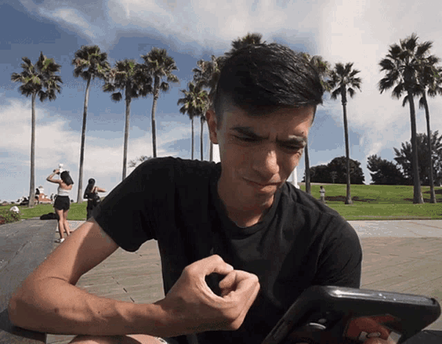 a man in a black shirt is looking at a cell phone