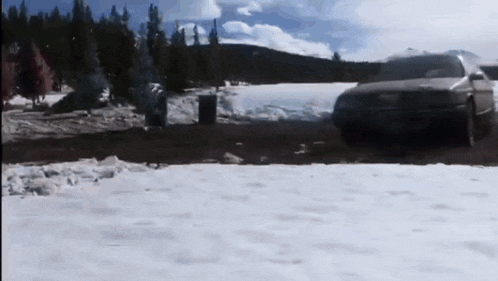 a car is parked in the snow near a forest