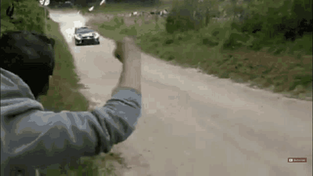 a man is pointing at a race car on a dirt road