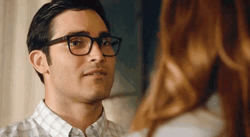 a close up of a man wearing glasses looking at a woman .