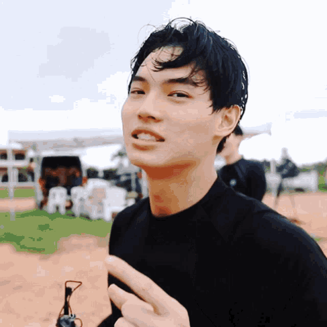 a young man in a black shirt is giving a thumbs up