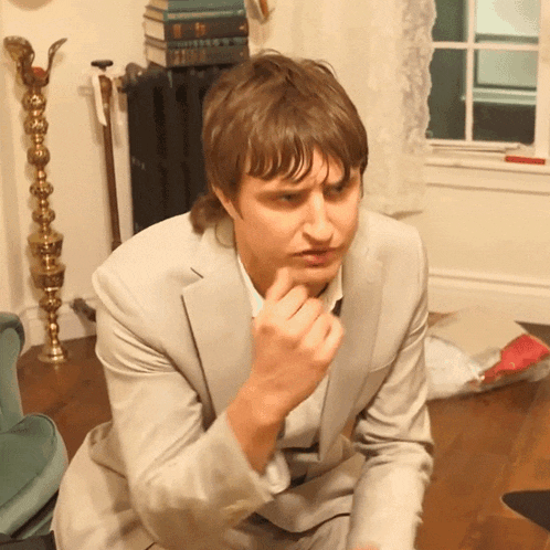 a man in a suit is sitting on the floor looking at something