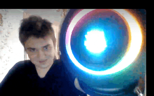 a young man stands in front of a large circle of light