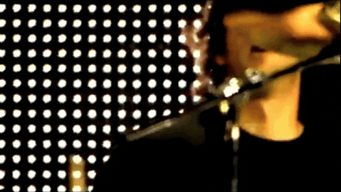 a person is singing into a microphone in front of a polka dot backdrop