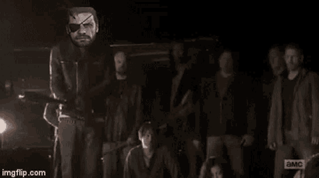 a group of people standing in a dark room with a man holding a gun in the foreground