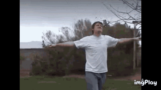 a man is standing with his arms outstretched in a park .