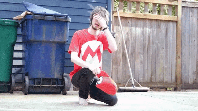 a man in a red shirt with the letter m on it is kneeling down