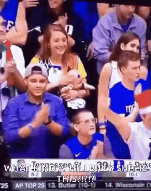 a group of people are sitting in a stadium watching a basketball game and a woman is holding a baby .