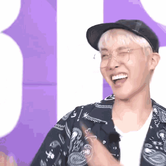 a man wearing a hat and glasses is laughing .