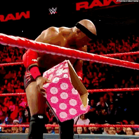 a man in a wrestling ring is holding a pink box