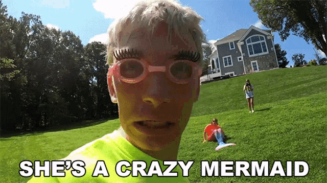 a man wearing glasses and a green shirt with the words she 's a crazy mermaid below him
