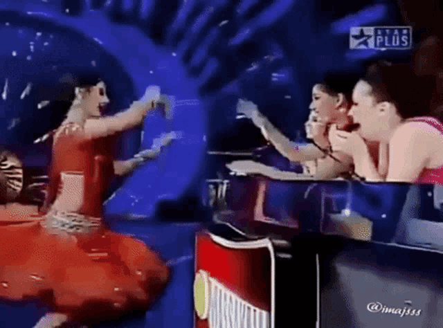 a woman in a red dress is dancing on a stage in front of a sign that says star plus .