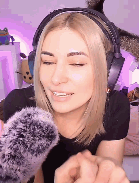 a woman wearing headphones and a microphone is smiling with her eyes closed