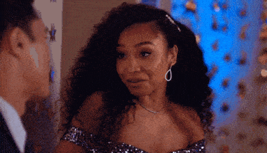 a woman in a sequined off the shoulder dress is looking at a man in a suit