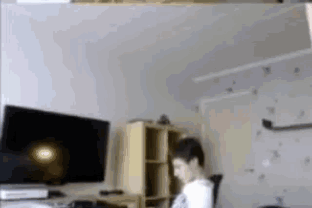 a man is sitting in a chair in front of a television in a room .