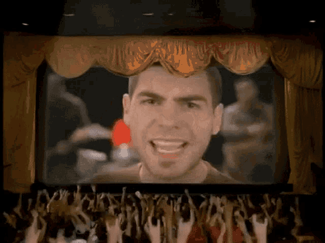 a man stands on a stage with a crowd behind him