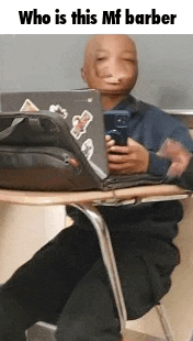 a bald man is sitting at a desk with a laptop and cell phone .