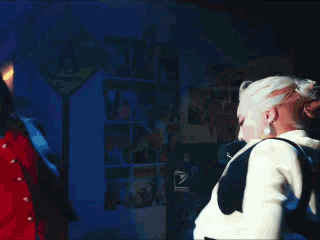 two women are dancing in a dark room with a blue light behind them