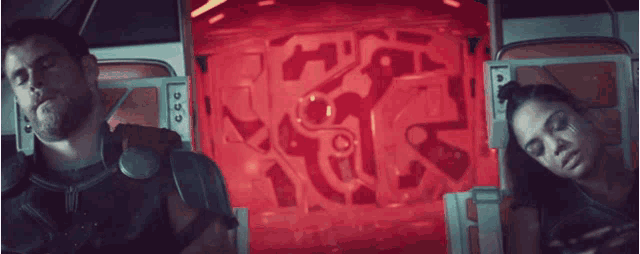 a man and a woman are in a room with a red light behind them
