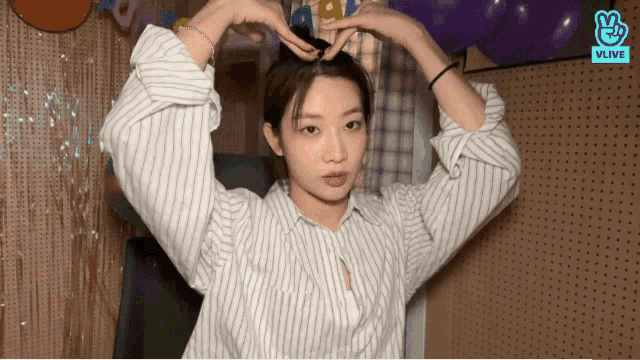 a woman in a striped shirt is holding her hair in a bun
