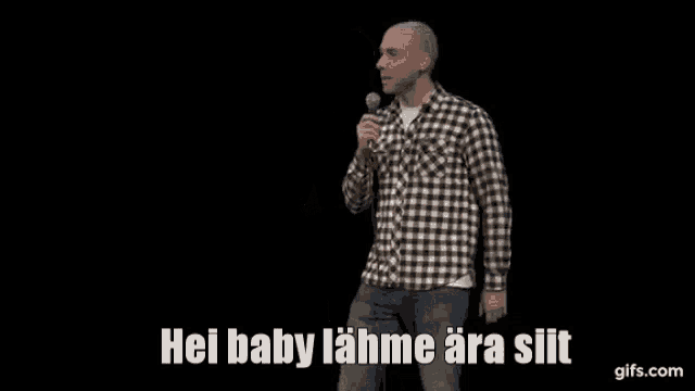 a man in a plaid shirt stands in front of a microphone and says hei baby lahne ara silt